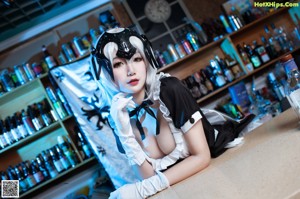 A woman dressed as a maid holding a bottle of liquor.