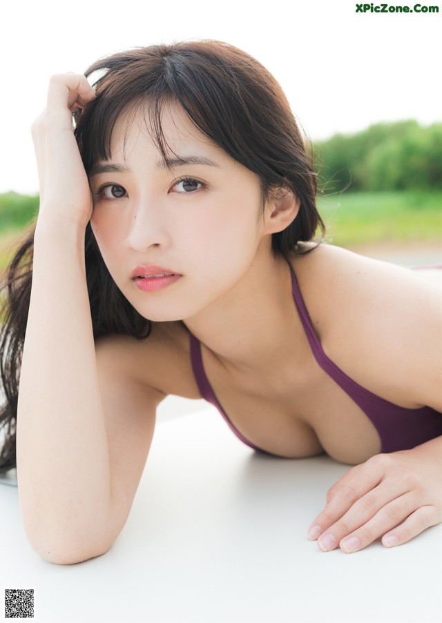 A woman in a purple bikini laying on a white table.