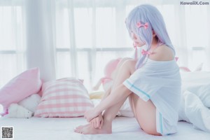 A woman laying on a bed in a white and pink outfit.