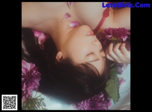 A naked woman sitting in a bathtub holding a pink object.