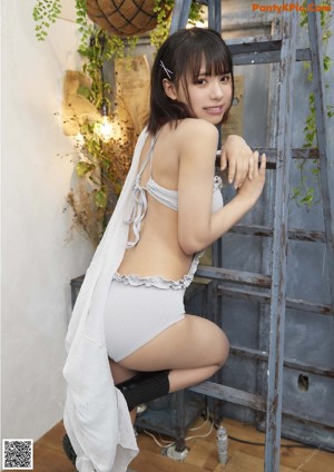 A woman sitting on a chair in front of a plant.