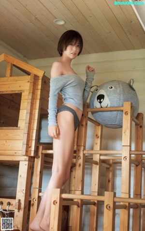 A woman in a blue bikini sitting on a bed.