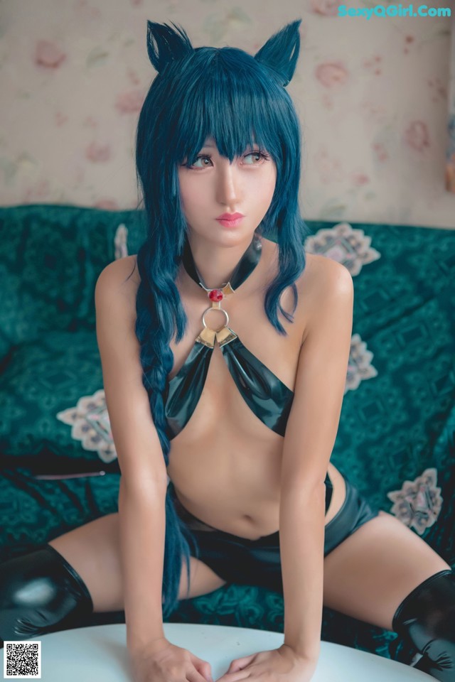 A woman with blue hair sitting on a green couch.