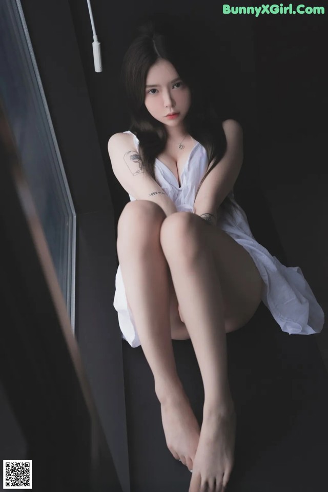A woman in a white dress sitting on a window sill.