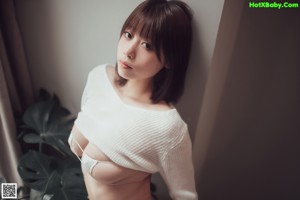 A woman sitting on top of a bed next to a window.