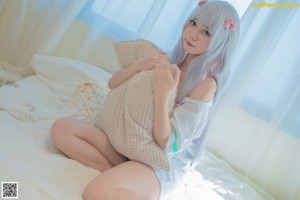 A woman sitting on a couch wrapped in a blanket.