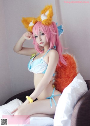 A woman in a blue and white bikini with pink hair.