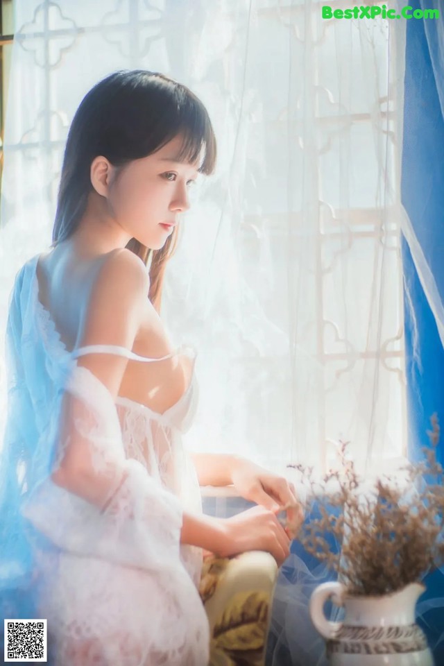 A woman sitting on a chair in front of a window.