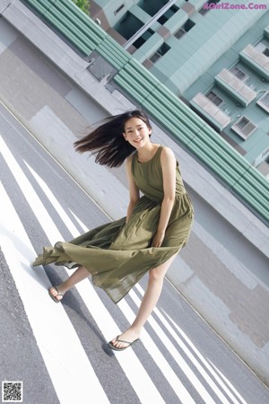 A woman in a green dress is standing on a zebra crossing.