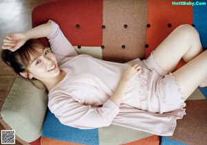 A woman in a pink tank top sitting on a couch.