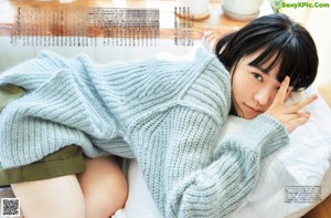 A woman laying on a bed covered in a blanket.