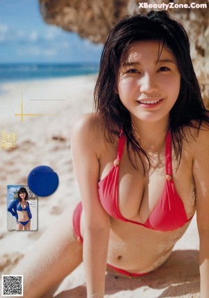 A woman in a blue bikini standing on a beach.