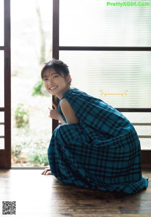 A woman in a blue shirt is looking out a window.