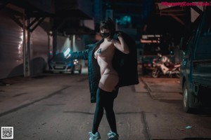 A naked woman wearing a mask sitting on the ground.