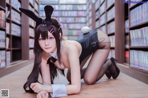 A woman in a bunny costume sitting on the floor holding a book.
