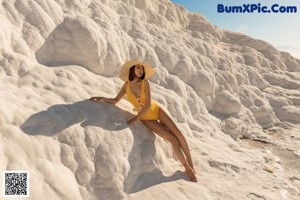 A woman in a yellow bathing suit and a straw hat.