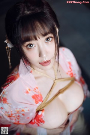 A woman in a pink kimono is tied up in a bathtub.