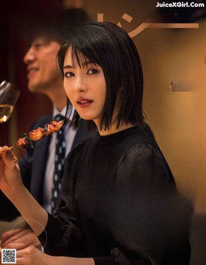 A woman eating a piece of meat on a stick.