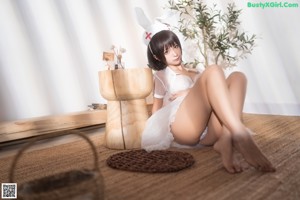 A woman in a white lingerie is sitting on the floor.