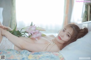 A naked woman laying on a bed with a bunch of flowers.
