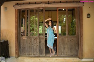 A woman in a blue dress sitting on a wooden table.