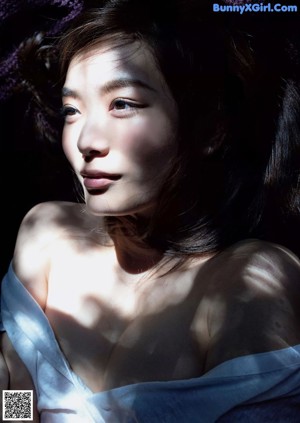 A woman in a black lingerie sitting on the floor.