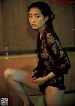 A woman in a black lingerie sitting on a wooden bench.
