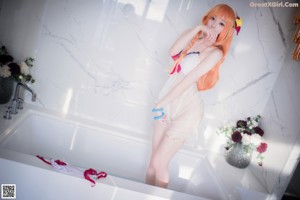 A woman with long orange hair wearing a white bikini.