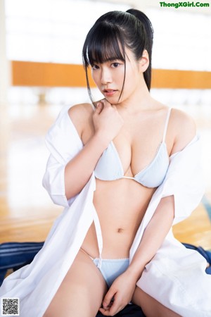 A woman in a white bikini holding a white shirt.