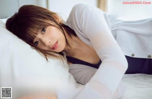 A woman sitting on top of a bed in a blue tank top.