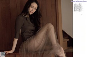 A woman with long brown hair is looking at the camera.