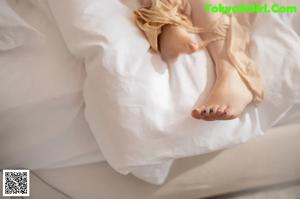 A woman in a tan lingerie laying on a bed.
