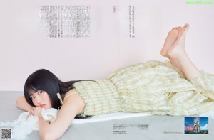 A woman sitting on the floor next to a white cabinet.
