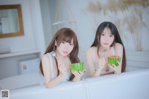 A couple of women sitting next to each other on a wooden floor.