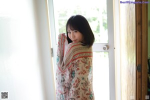 A naked asian woman is posing under a blanket.